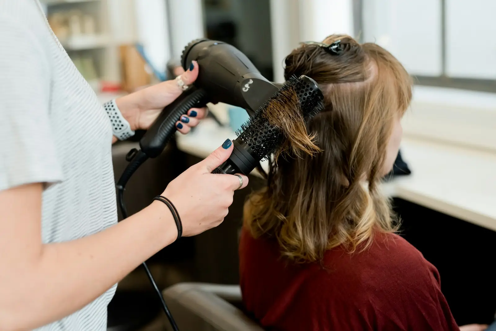 Stylist blow-drying a client's hair in the salon